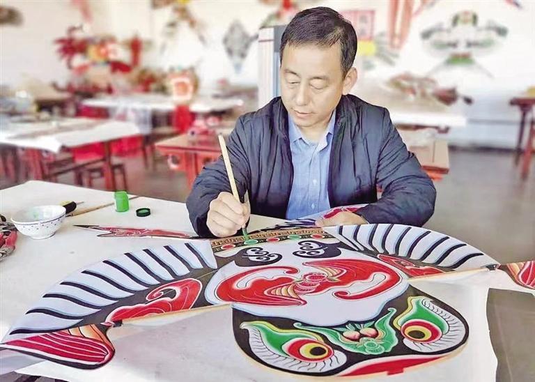 赵艳强正专心绘制风筝.