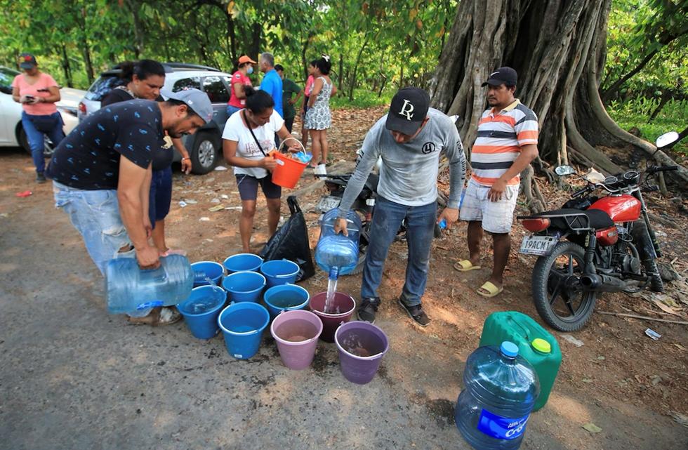 ▲志愿者在水桶里装满水提供给动物