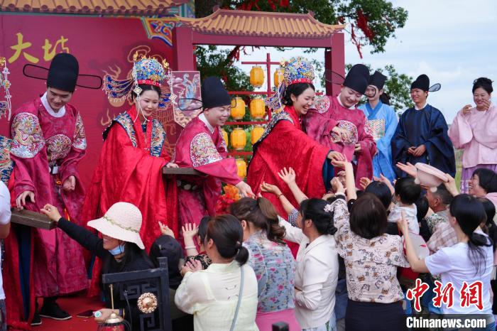 5月20日，江西省金溪县6对新人举行集体婚礼，倡导婚嫁新风。图为新人为现场亲友发糖。江西省婚姻家庭协会供图
