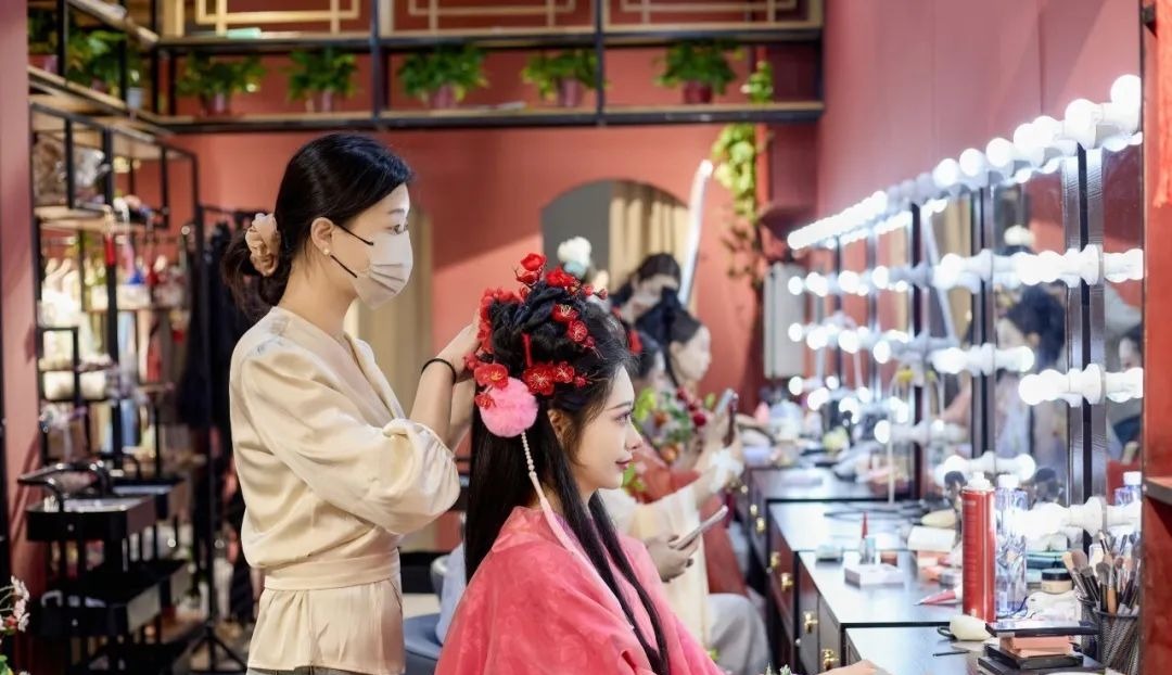 汉服体验馆的妆造师(左)正在为顾客打扮.