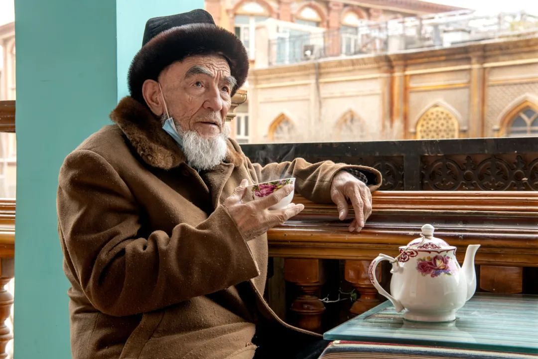 ▲在喀什百年老茶馆二楼的露台走廊，慈祥的老茶客在品茶。　2021年摄