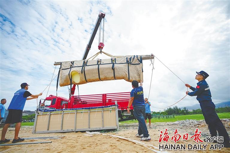 工作人员将装有领航鲸模型的水槽抬起。海南日报记者 王程龙 摄