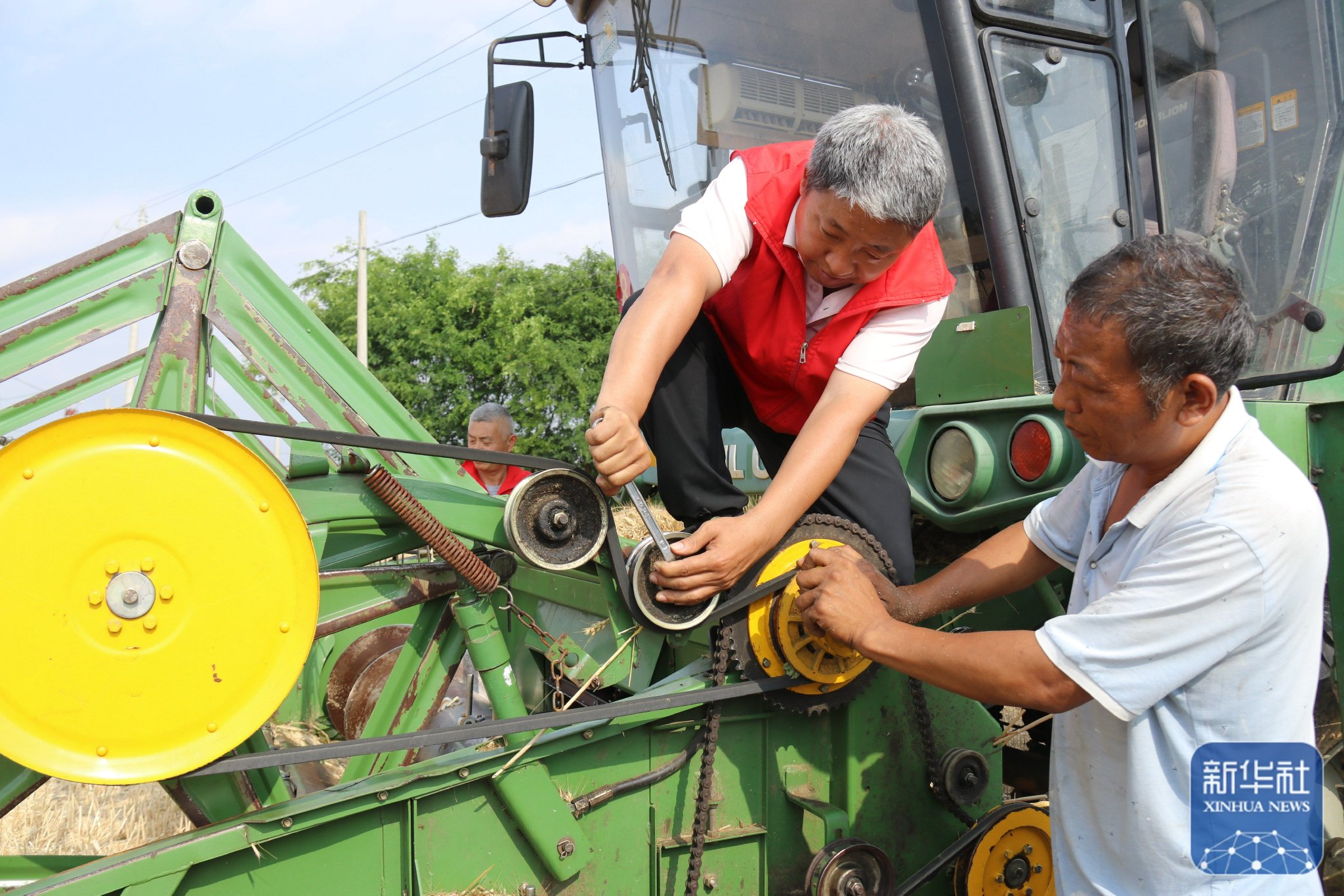 5月26日,在河南省南阳市内乡县大桥乡,农机服务人员(右二)为跨区作业
