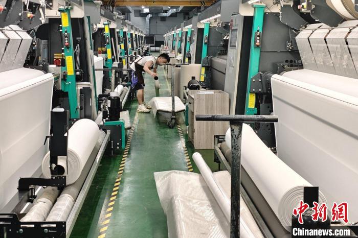 5月27日,晋江市七彩狐服装织造有限公司的自动化生产线正快速运转.
