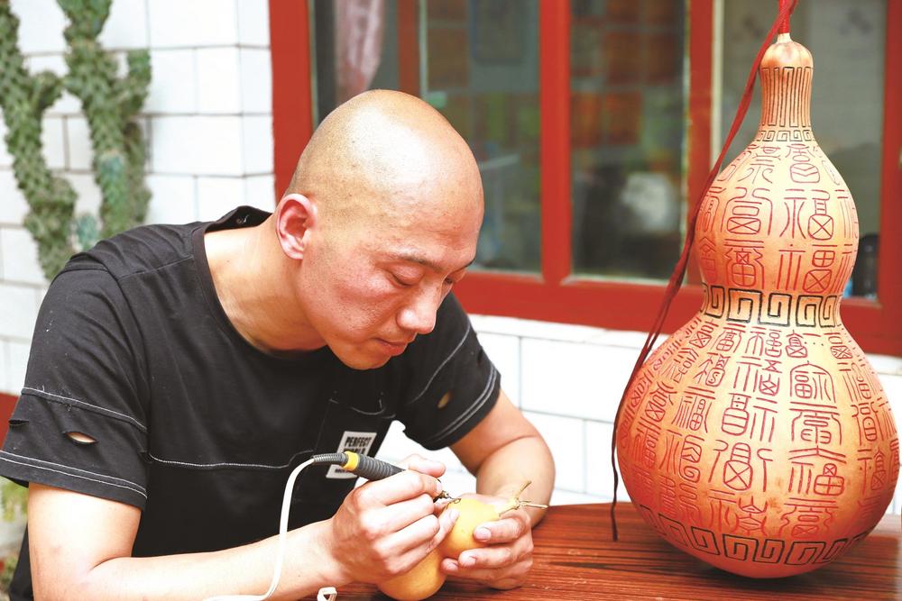 曹建正使用电烙铁进行烙画.烙铁代笔,以火为墨.