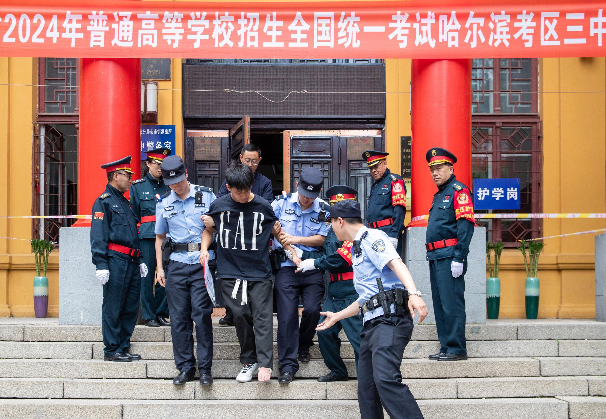 6月7日,在哈尔滨市第三中学考点,一名脚部受伤的考生在工作人员搀扶