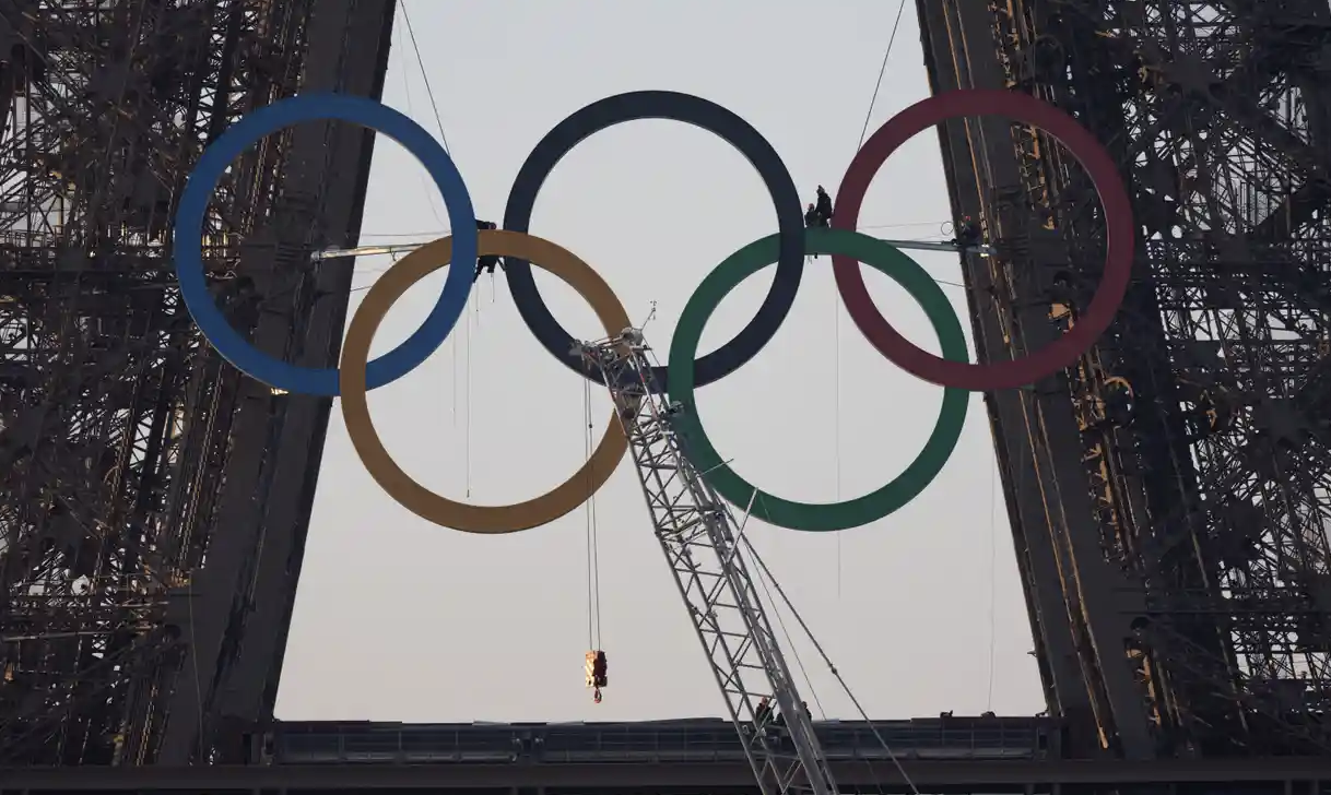 奥运五环的雕塑被吊在埃菲尔铁塔上。（图源：社交媒体）