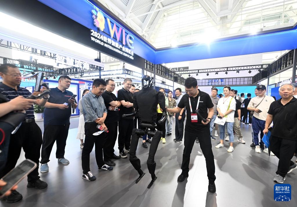 　　6月21日，工作人员在博览会上和一款仿生机器人互动。