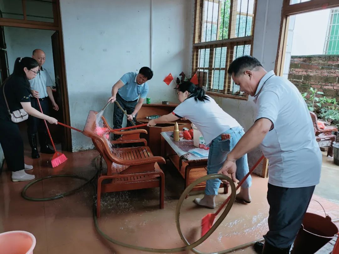 镇村干部帮助居民清理屋内积水。