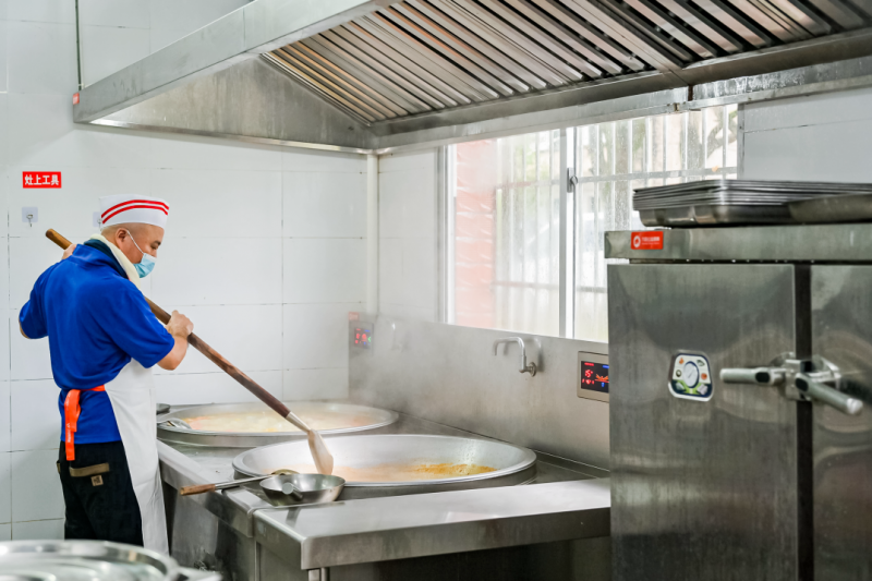 公益厨房内,工作人员在为学生准备餐食.
