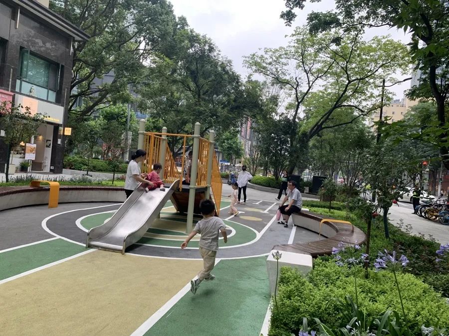 儿童乐园,橙黄色的攀爬架,滑滑梯等游乐设备与黄绿间隔的橡胶跑道色彩