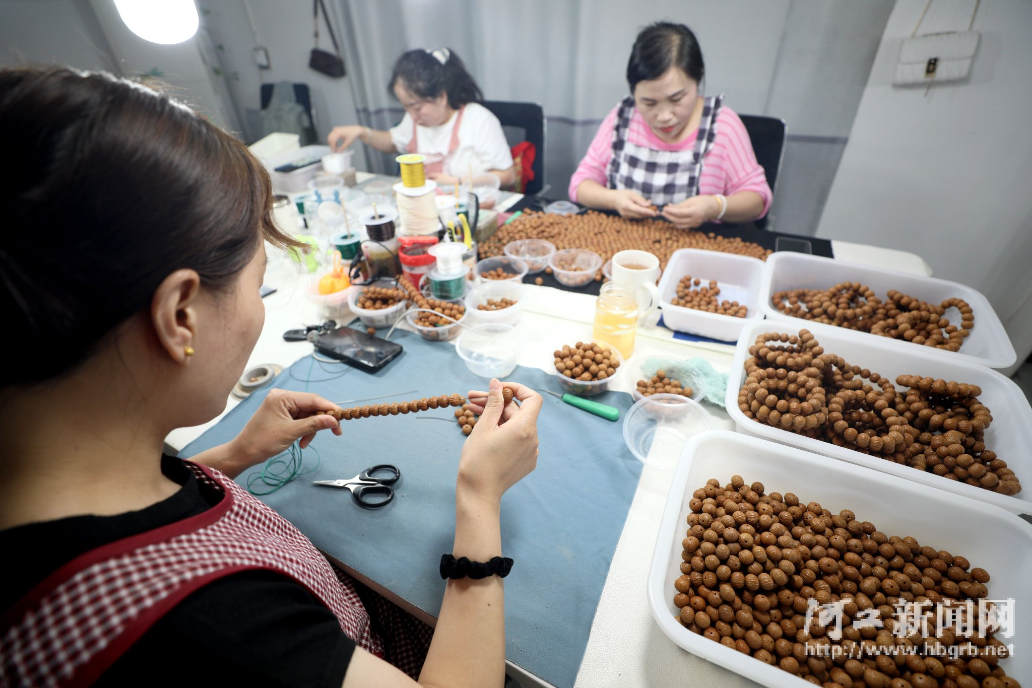 7月11日,在邢台市隆尧县隆尧镇一家手串加工厂,工人正在制作文玩核桃