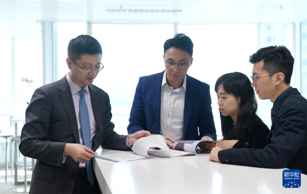 部执行负责人许佳(左一)在位于香港国际金融中心的办公室里和同事交谈