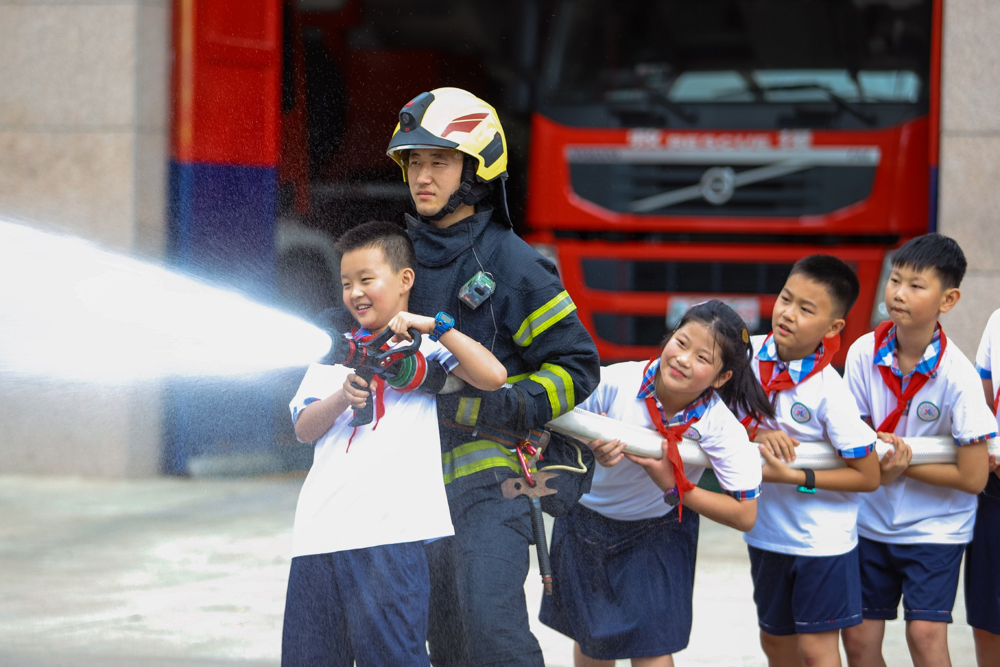 学生在消防员的指导下体验手持水枪"灭火".通讯员 张鹰 摄