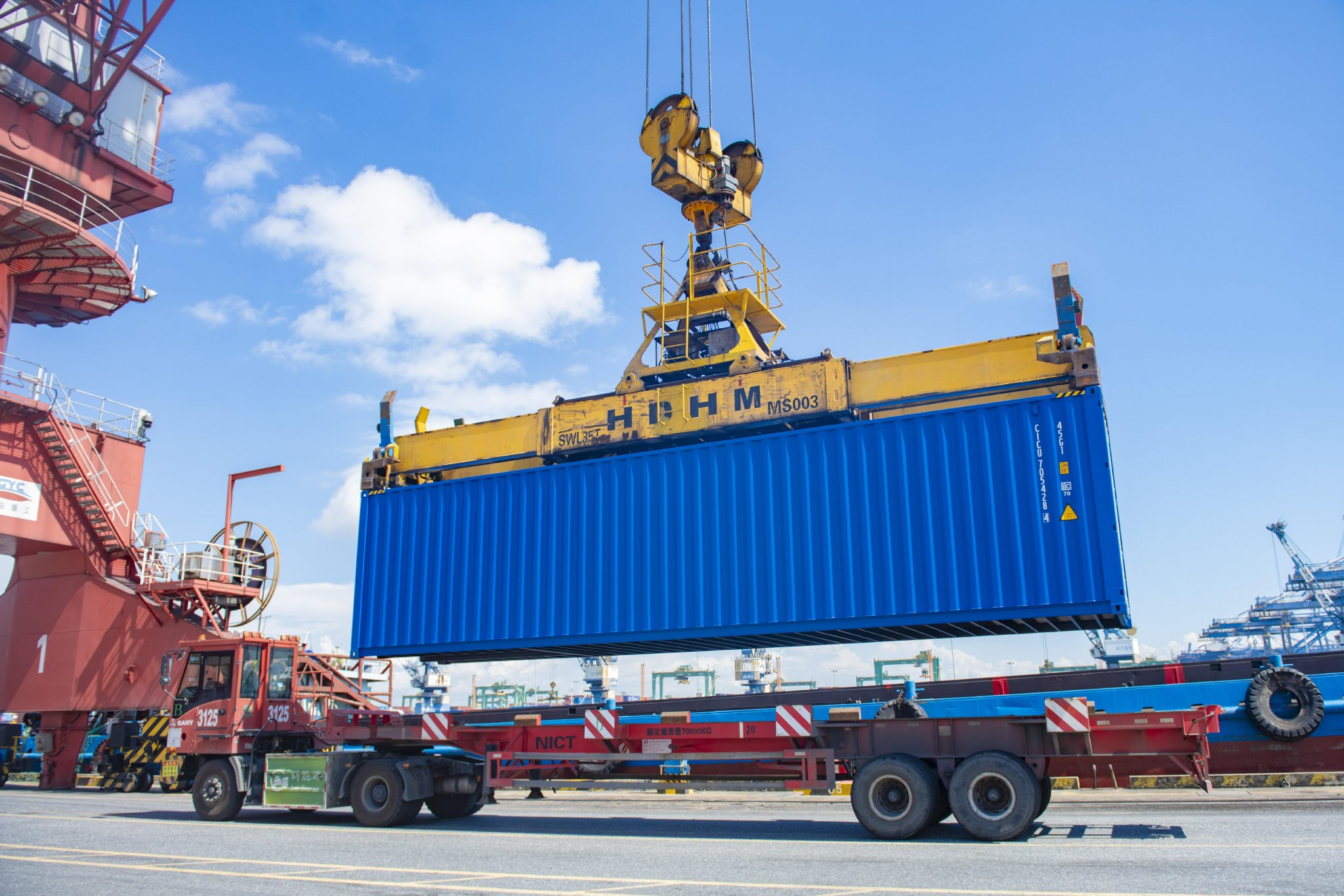 在广州港南沙集装箱码头,装载货物的集装箱正从接驳船上卸下转运.