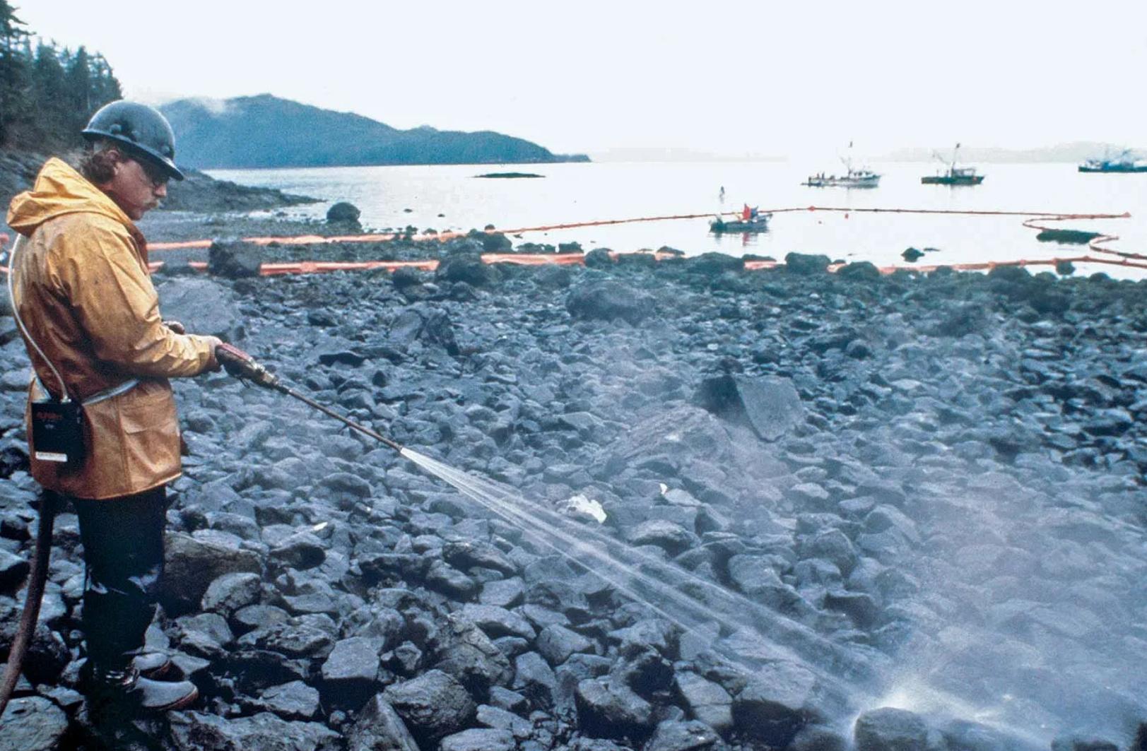 (工人们正在用高压水枪冲洗被原油染黑的海滩,来源:美国海岸警卫队)