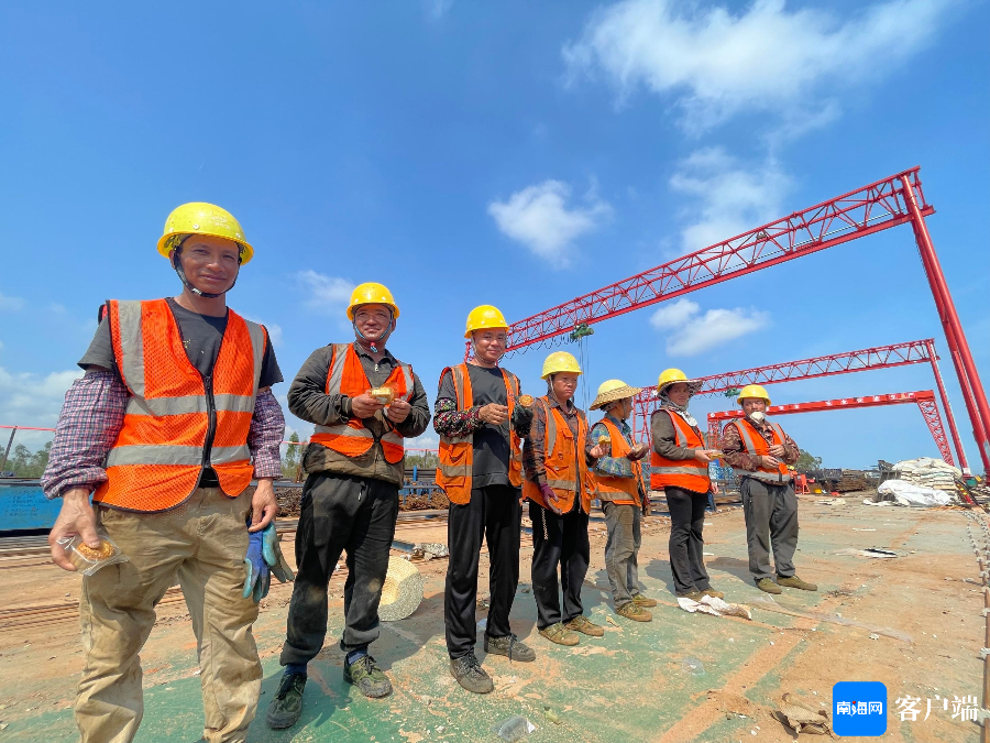 在洋浦疏港高速公路sg01标施工现场,工作人员在工地上品尝着月饼.