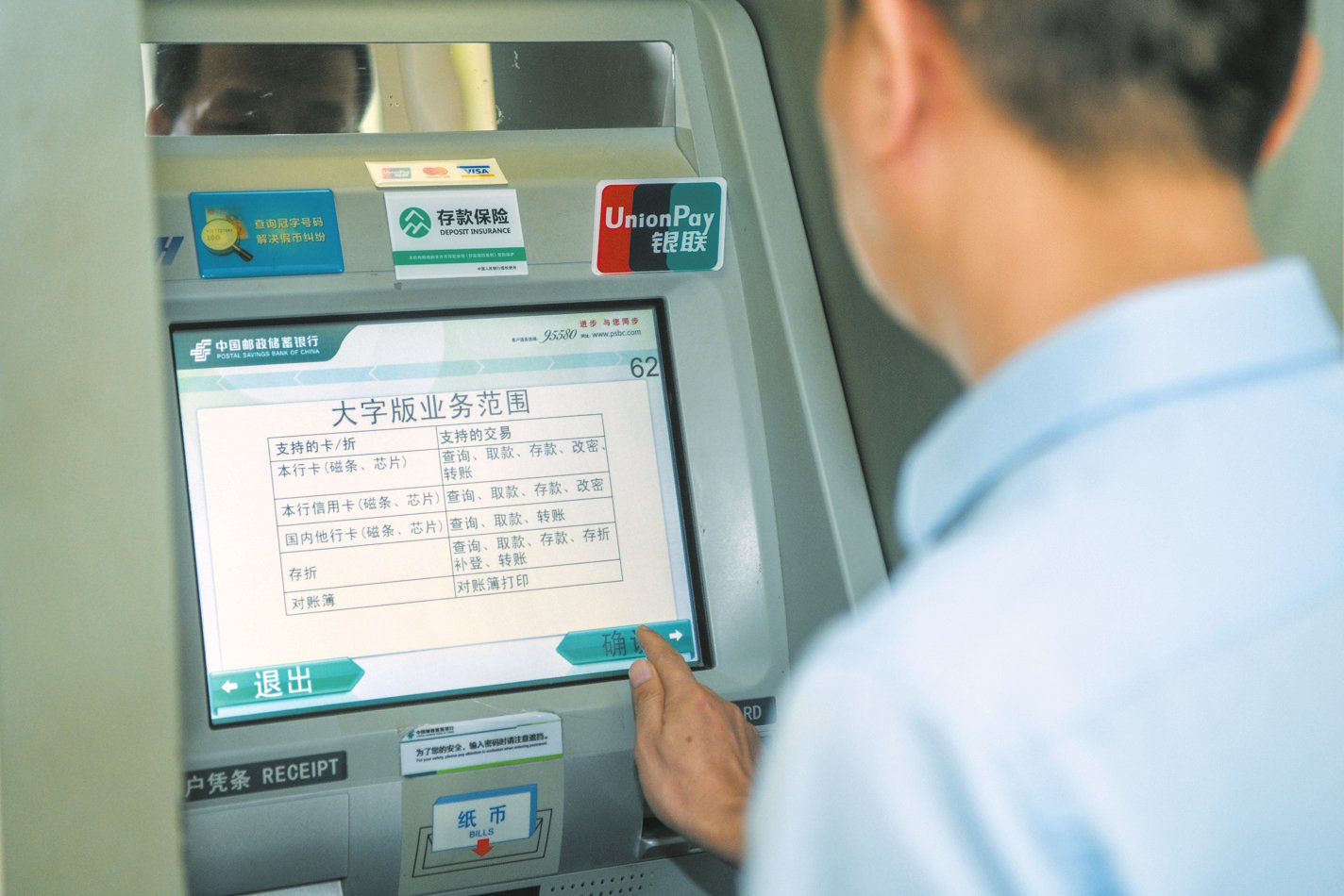 银行工作人员演示自动取款机"大字版"界面切换方式