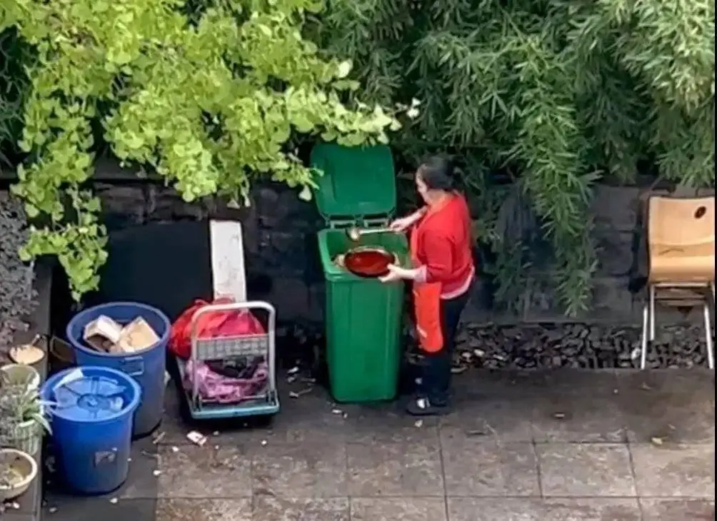女子从垃圾桶里舀油。