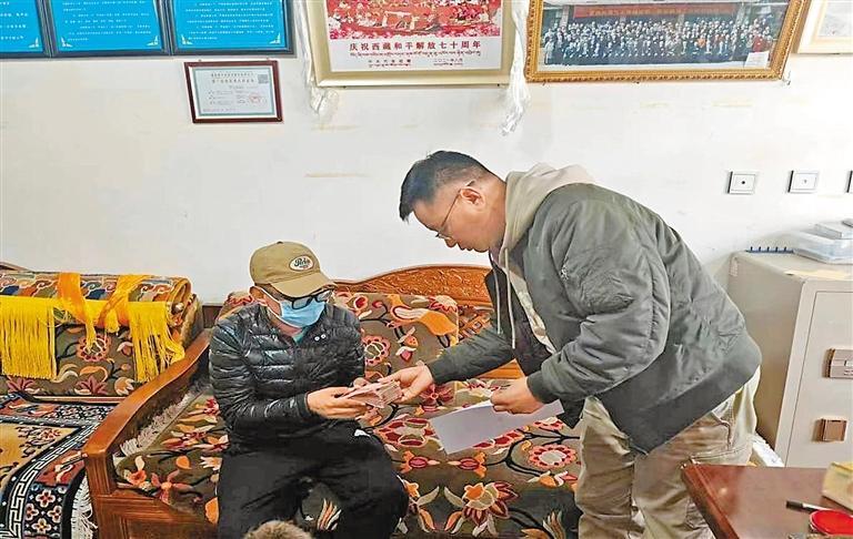 拉萨市冲赛康社区工作人员将帮扶慰问金送到困难党员拉巴次仁手中.