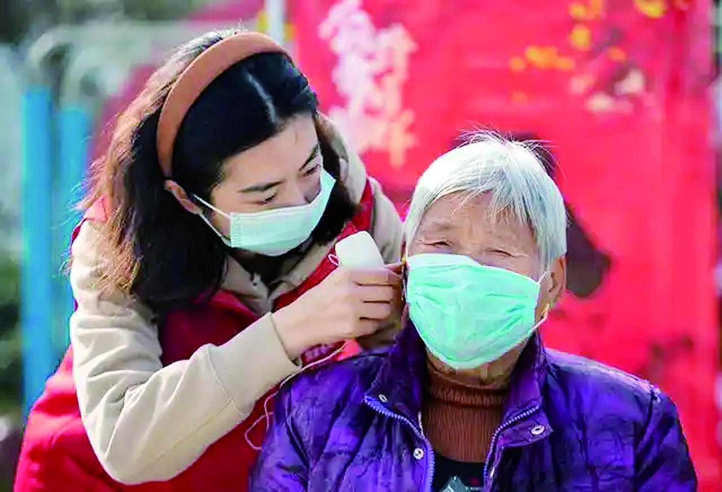 志愿者为老人佩戴免费的助听器