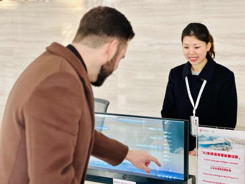 （图为外国游客正在体验AI智能翻译屏）