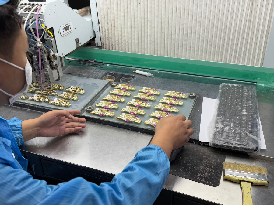 （工人正在为十五运会冰箱贴上色）