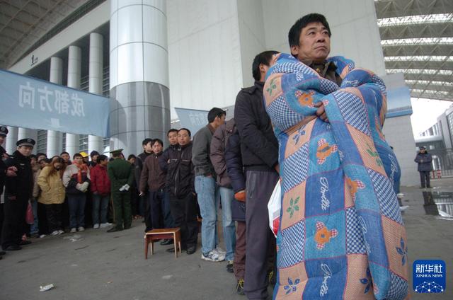 2009年1月2日，在宁波国际会展中心春运临时售票点，一名排了两天队的购票者披着棉被等待买票。 新华社发（张培坚 摄）