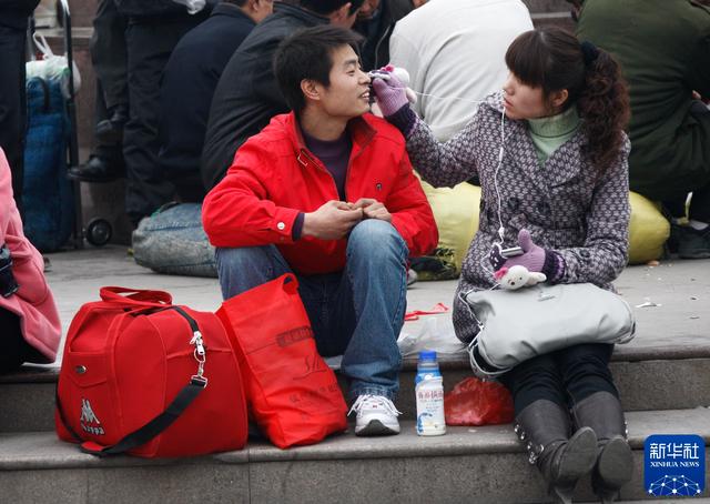 2010年1月30日，在上海火车站站前广场，一对候车的情侣一起分享音乐。新华社记者 裴鑫 摄