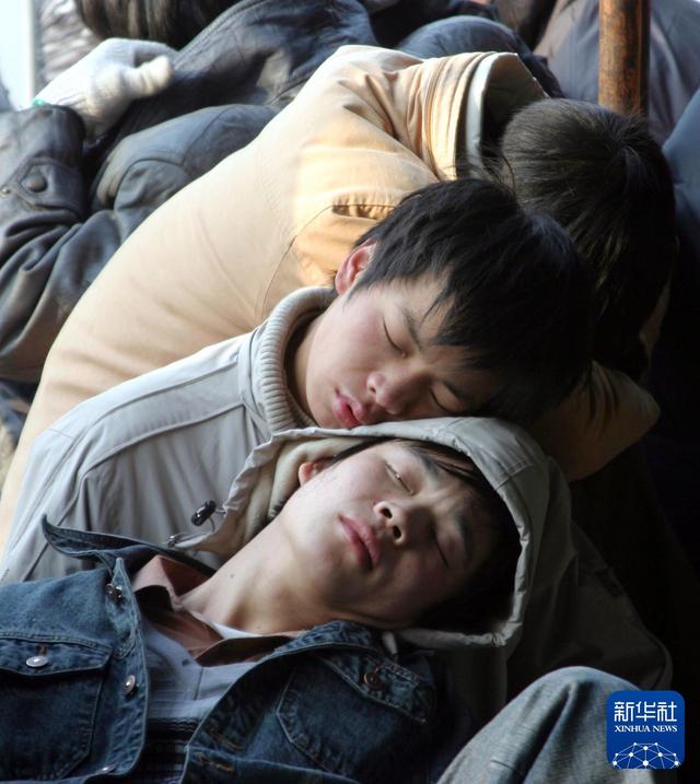 2005年1月17日，几名外来务工者在温州火车站临时售票处前休息，等待购买回家的火车票。新华社发（卢春雨 摄）