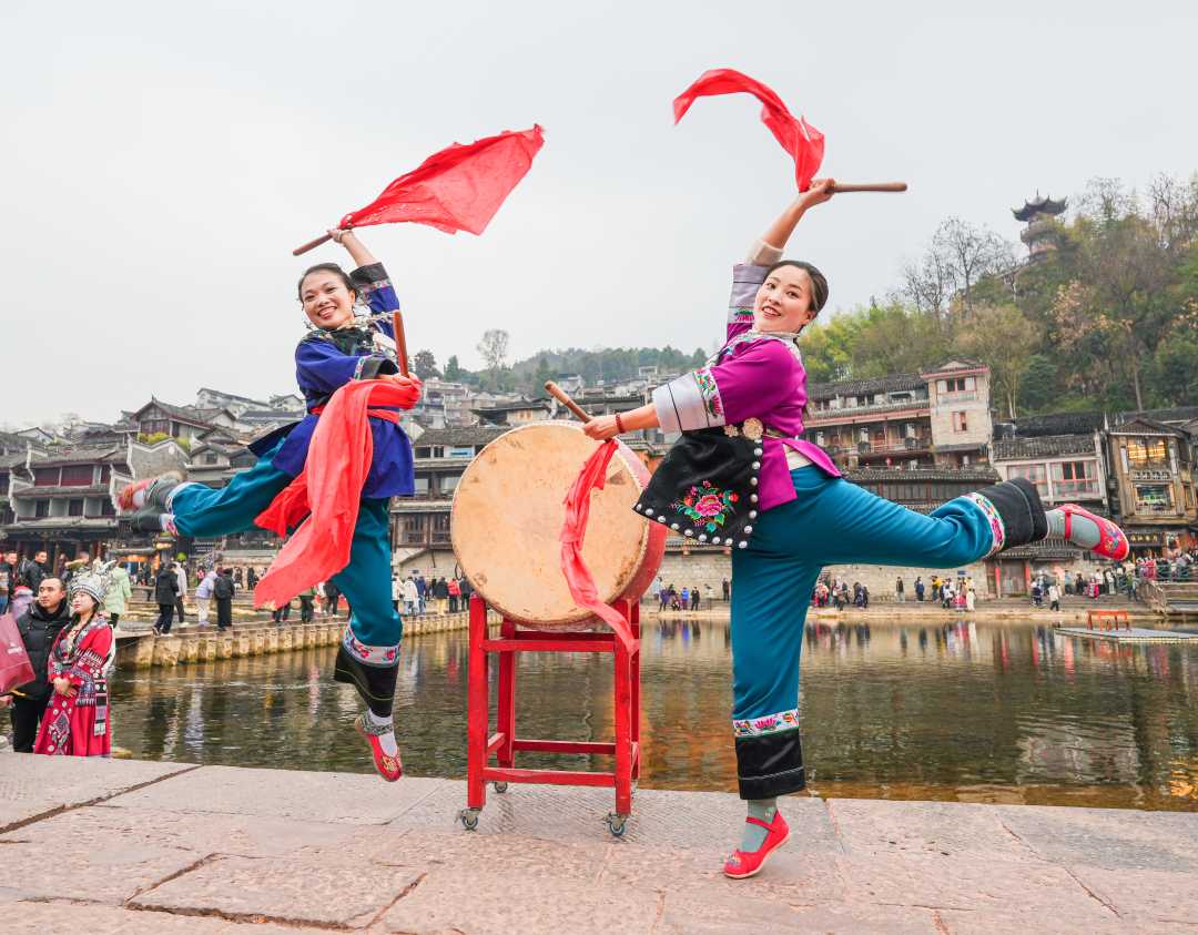 1月30日,湖南省凤凰县凤凰古城,苗家姑娘在沱江河畔用欢快优美的苗族