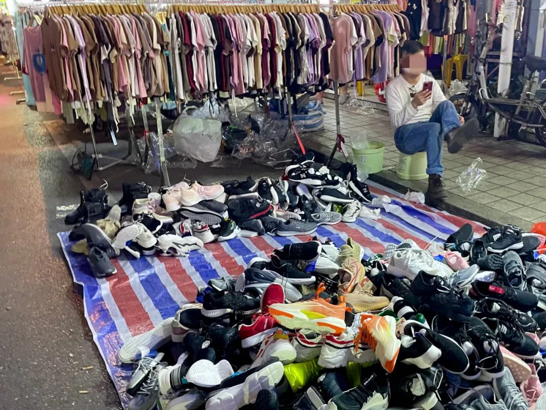 夜晚，南村城中村内，人们支起简易小摊售卖衣服，最简陋的是地上铺块布，衣、鞋堆成小山。摄影/郑可书