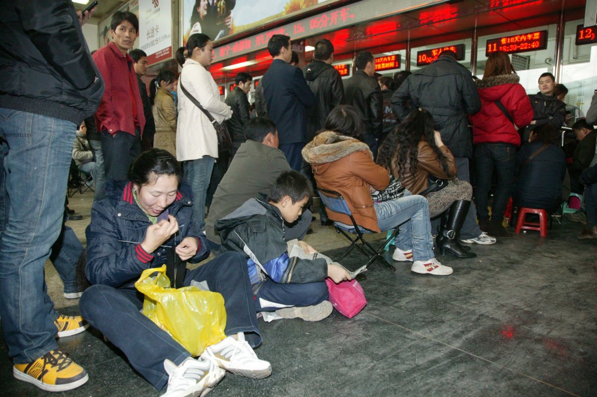 2011年,旅客在南宁火车站售票处自备小板凳排队购票