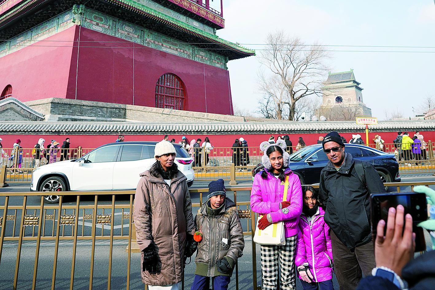 在北京鼓楼东大街，来自马来西亚的一家游客与钟鼓楼合影留念。