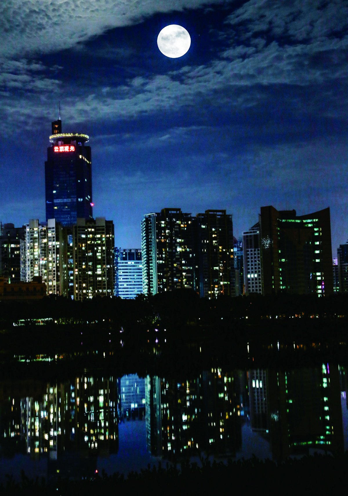图为"超级月亮"在南宁市南湖上空升起