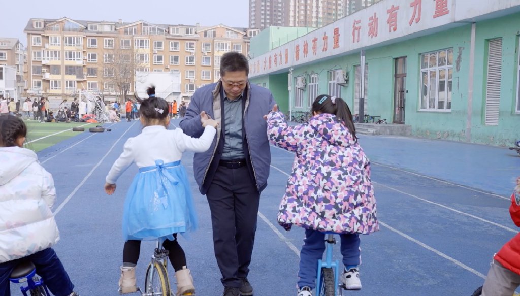 侯明飞校长正在陪学生们练习骑独轮车。