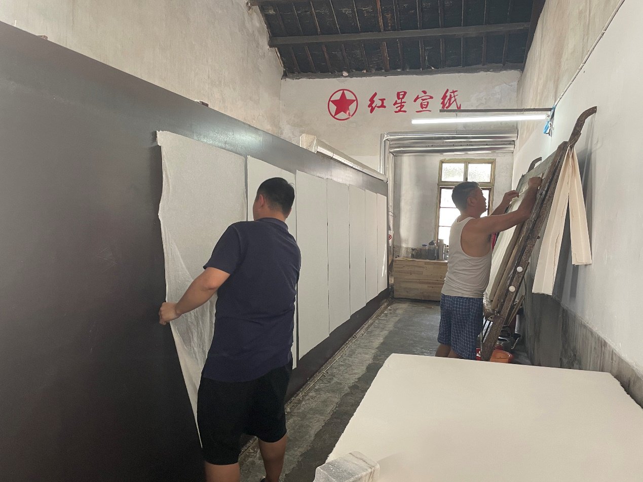 ▲2月的泾县冬寒未散，红星宣纸工厂内，身着背心、短裤的晒纸工正在晒纸。树森▕摄