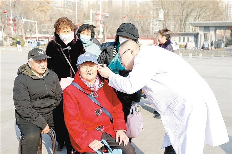 义诊现场,医生为老年人检查听力。本报记者 刘飞 本报通讯员 任涵 摄