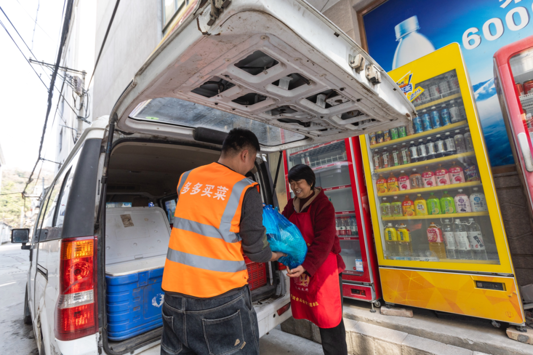 陈建良将当日货品交至提货点团长。摄/苏巧将