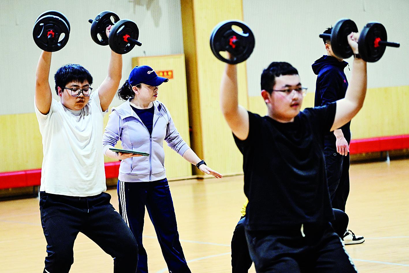 在中国农业大学东校区，减脂课教师刘莹（左二）指导学生进行力量训练。