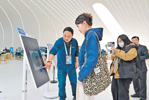 参观者在工作人员的帮助下体验AI识别面部生成个人画像。 实习记者 金瑶摄