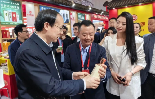 成都市副市长陈志勇（左）向金盆地集团董事长余刚（中）询问“一品江山”酒的生产和市场反馈情况