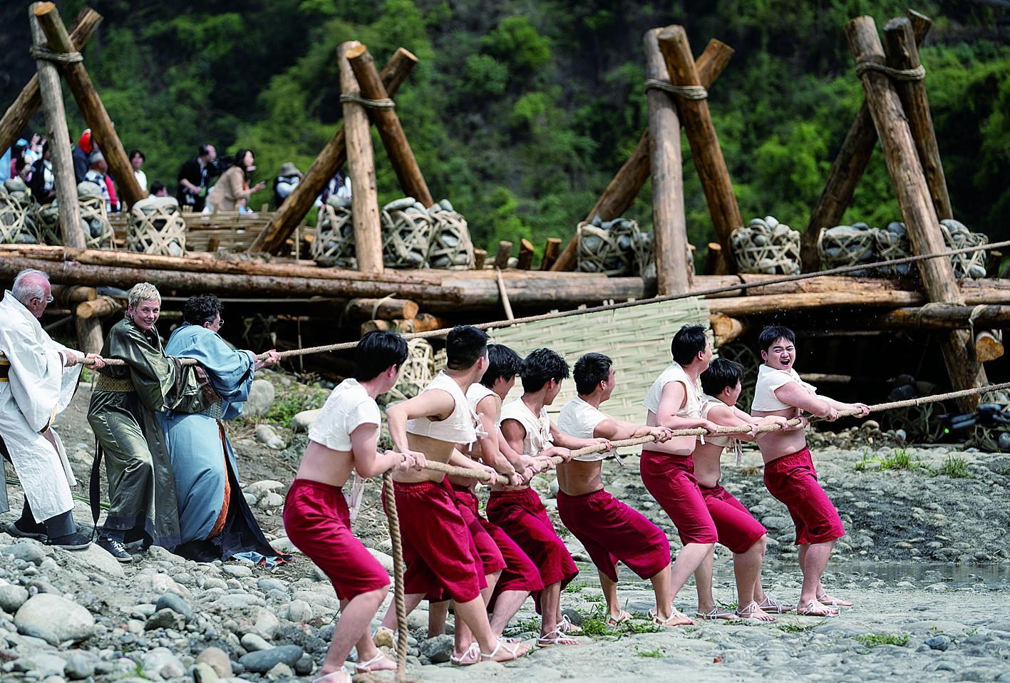 外国嘉宾与堰工一起拉绑在杩槎上的绳索 新华社发