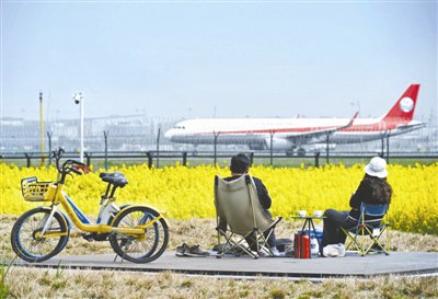 ▲飞机冲刺在成都双流国际机场跑道上，市民在环港绿洲公园看飞机起降 摄影 王效