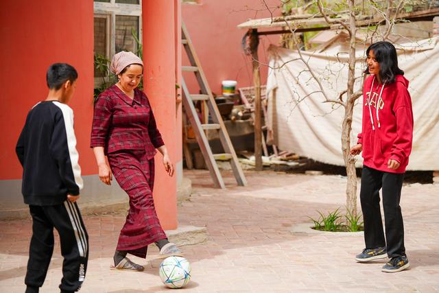 Young girl playing soccer with family in the yard