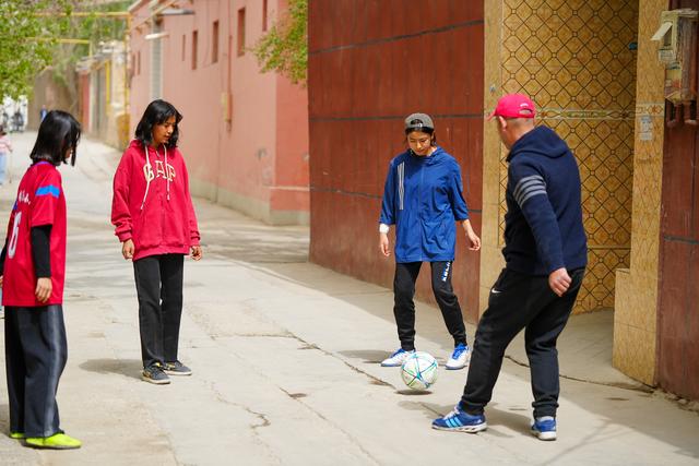 Young girl playing soccer with family