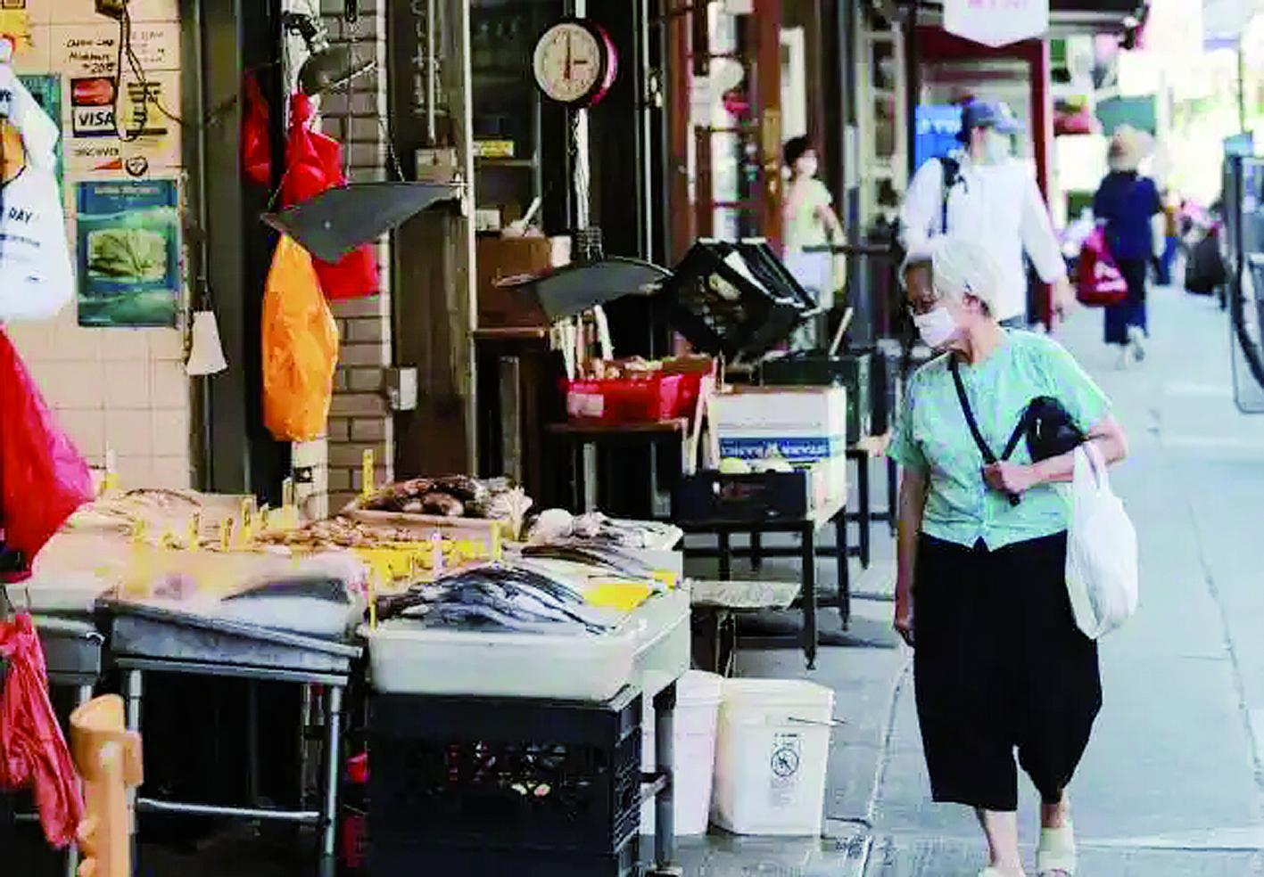 行人从美国纽约曼哈顿唐人街上的一家海鲜店旁走过 新华社发