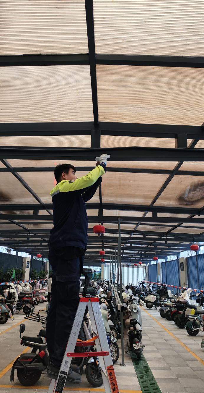 图为：万科物业在管小区的电瓶车棚正在加装智能烟雾传感器