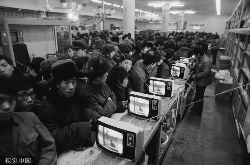1985年，地点未知，电视机售卖商店内，人们排着队等待购买电视机。John Downing/摄