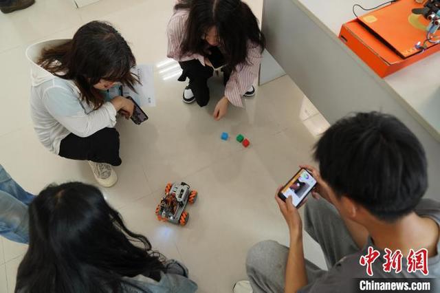 图为参展商向参观者展示智能分拣小车模型。王继军 摄